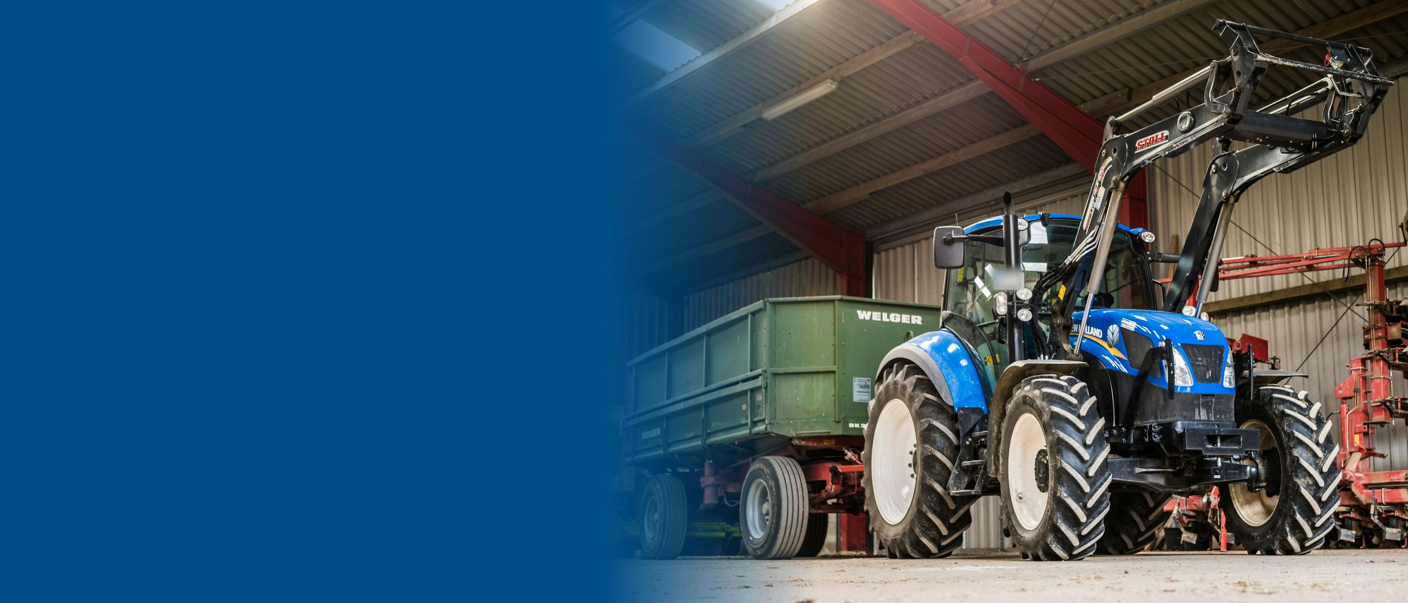Blue tractor with front loader in a farm shed